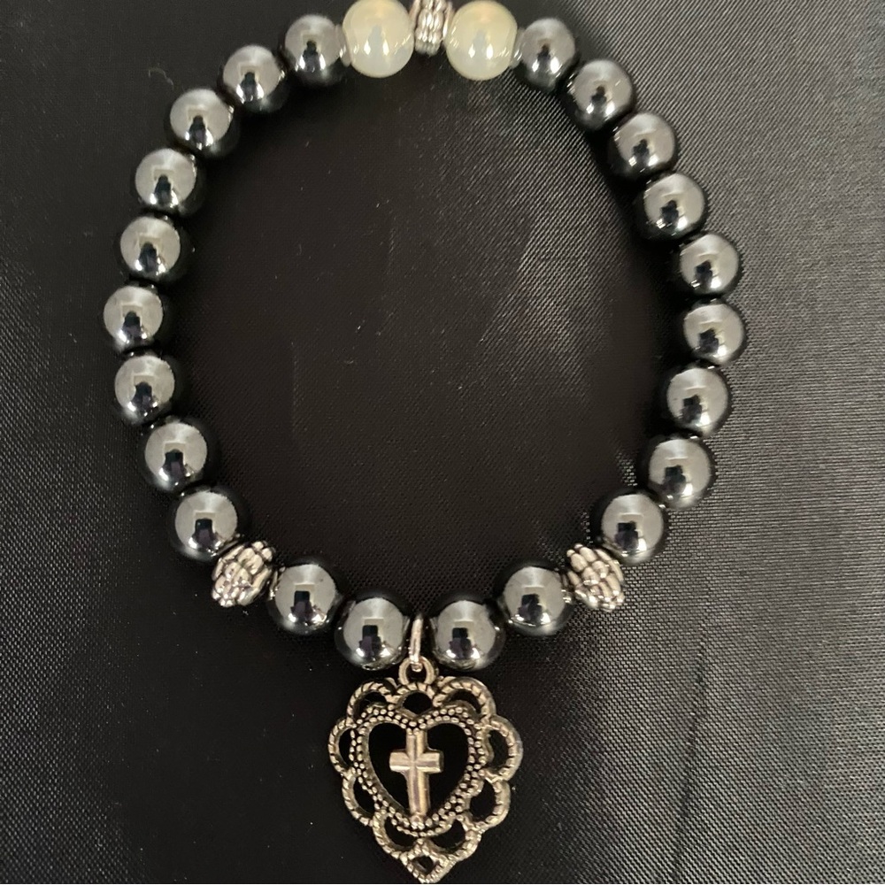 Bead Bracelet With a Heart Shaped Charm Featuring a Cross.